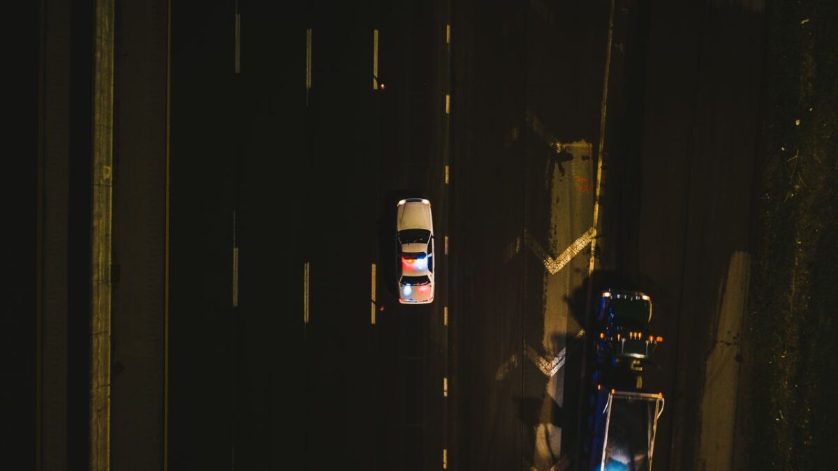Police cruiser with flashing lights on a dark highway at night