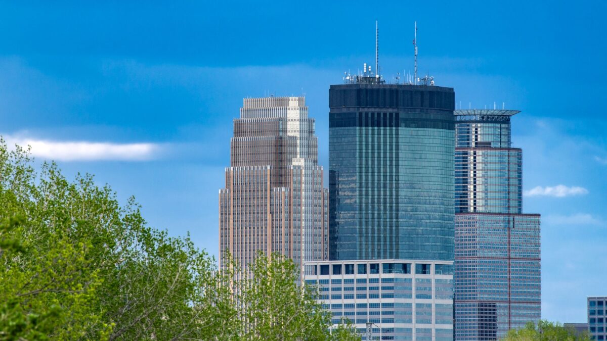Minneapolis skyscrapers framed by greenery under a blue sky