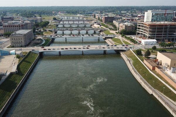 Aerial view of downtown Des Moines, Iowa, with the river and bridges under a clear sky