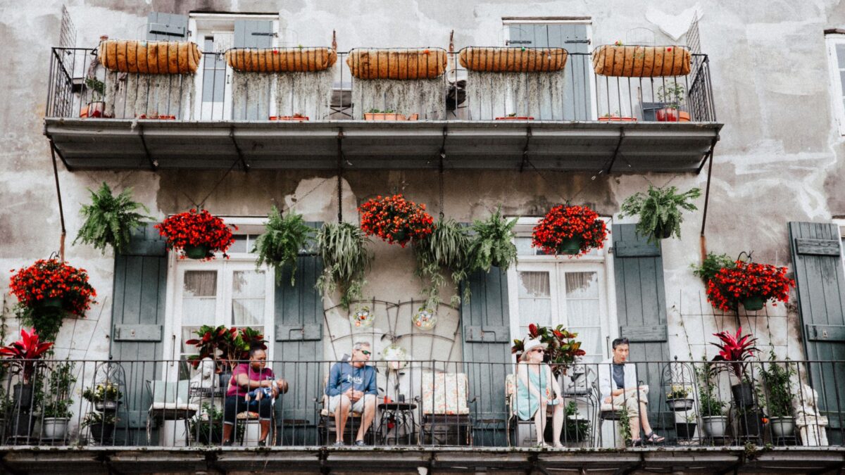 Travelers relaxing on a flower-covered French Quarter balcony in New Orleans