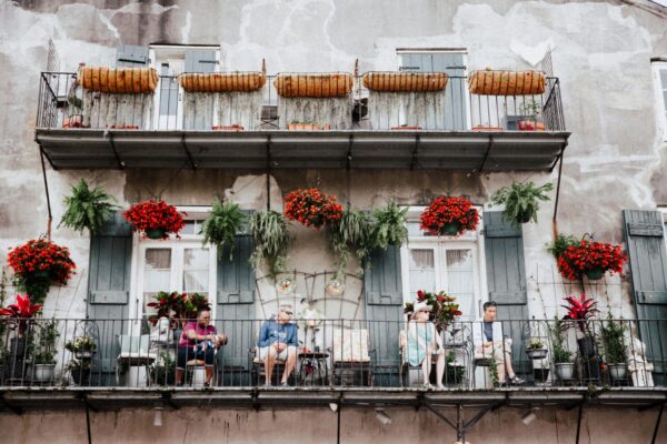 Travelers relaxing on a flower-covered French Quarter balcony in New Orleans