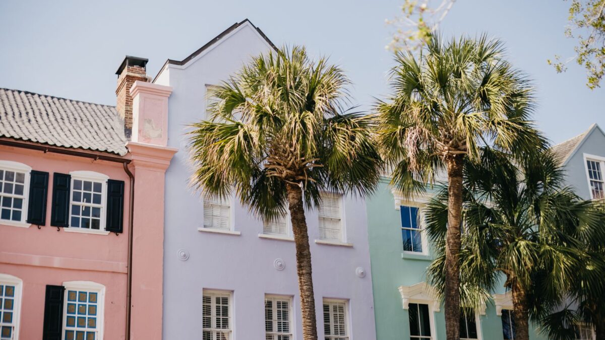 Pastel historic homes and palm trees on a sunny street in Charleston, South Carolina