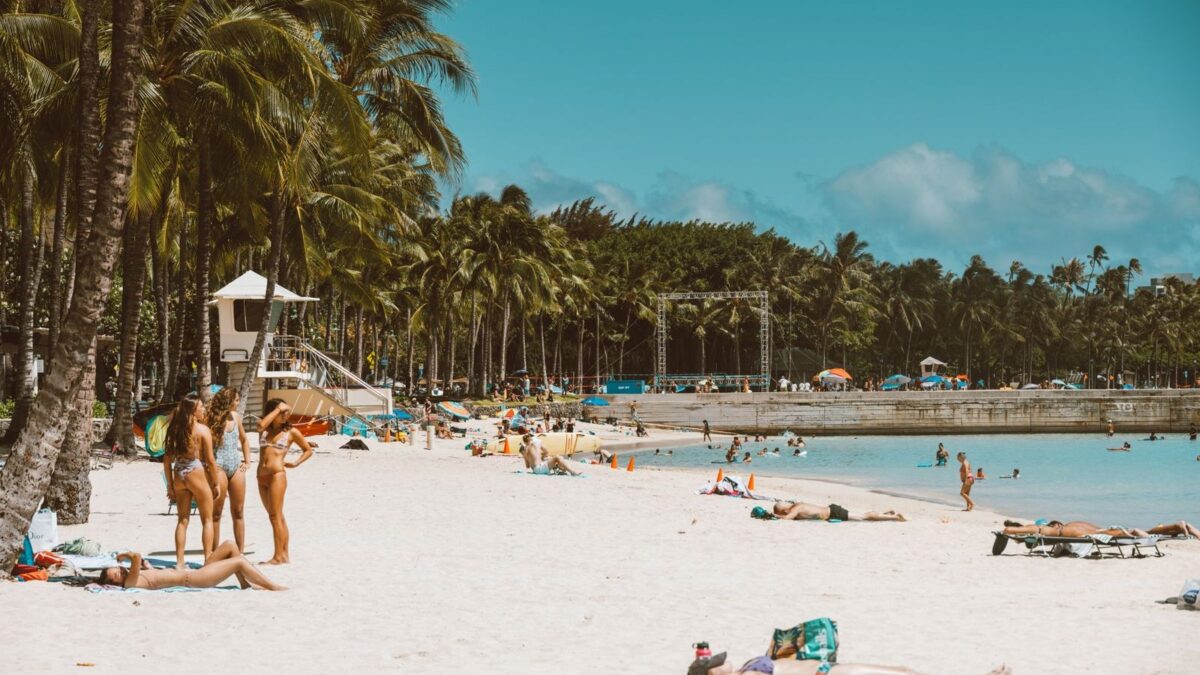 Waikiki beach in Honolulu with palm trees, white sand, and swimmers in turquoise water