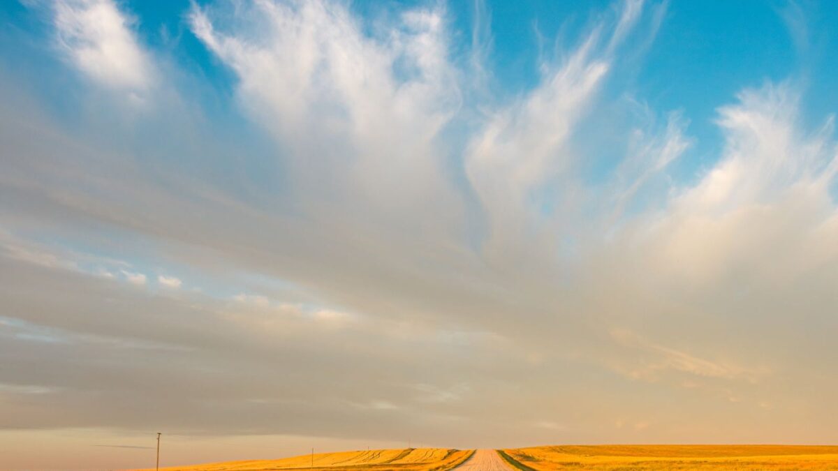 Open prairie road under a dramatic sunset sky