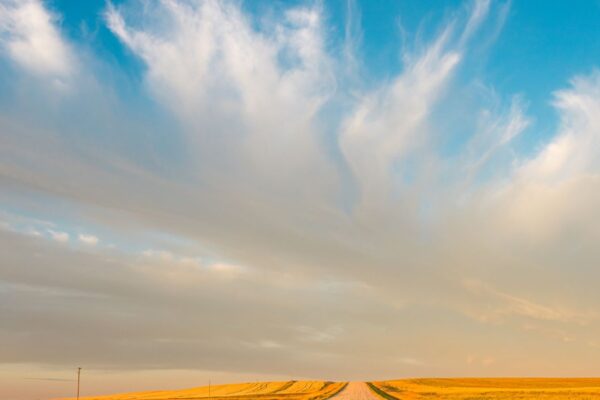 Open prairie road under a dramatic sunset sky